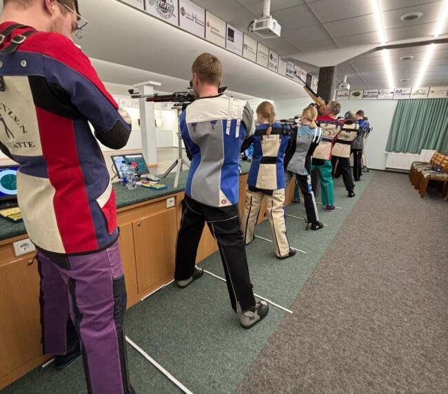 Mehrere Personen zieheln mit langwaffen auf eine Zielscheibe