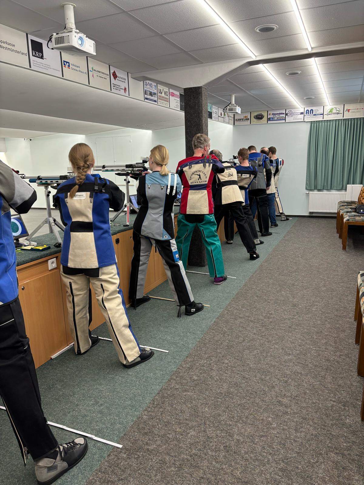 Mehrere Personen zieheln mit langwaffen auf eine Zielscheibe