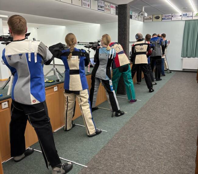 Mehrere Personen zieheln mit langwaffen auf eine Zielscheibe