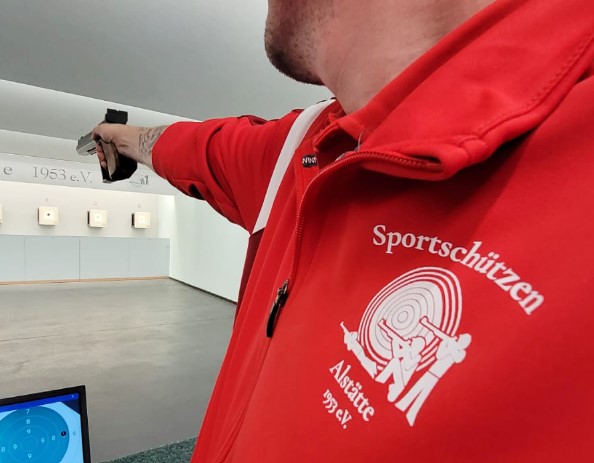 Logo auf Jacke im Fokus während ein Mann auf Ziel schießt